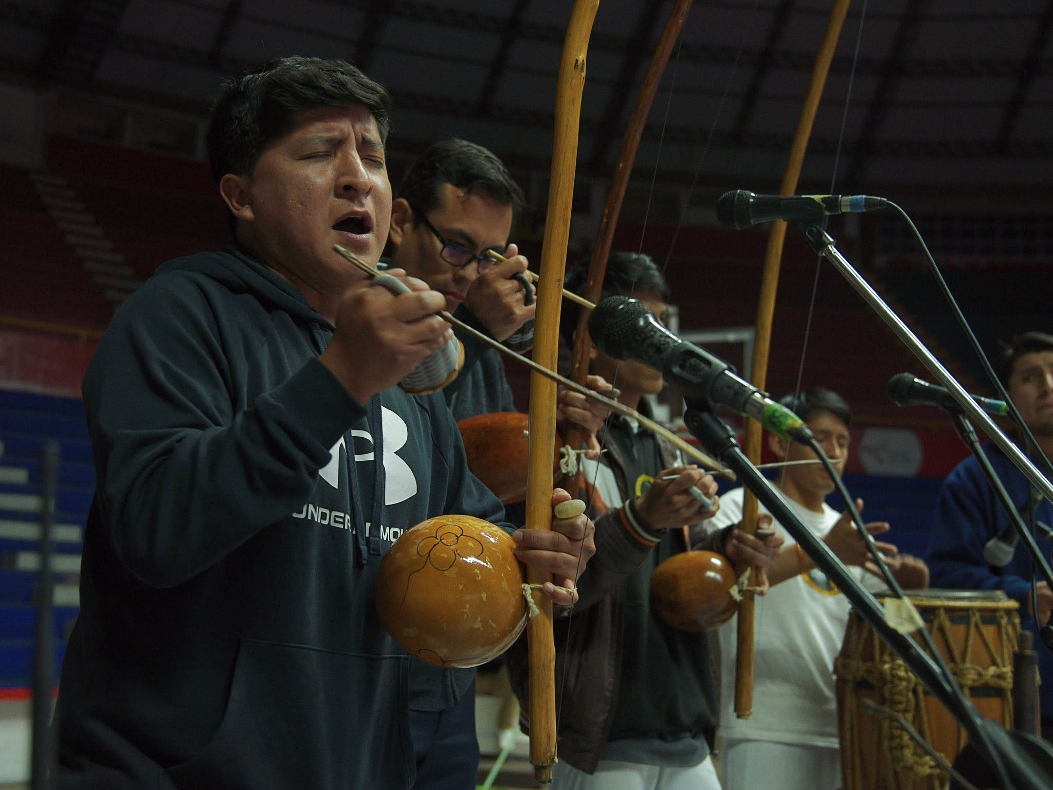 Músicos de capoeira cantando y tocando berimbaus